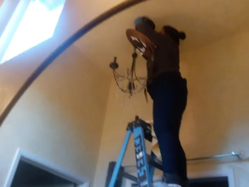 Electrician installing a chandelier in a Lake residence